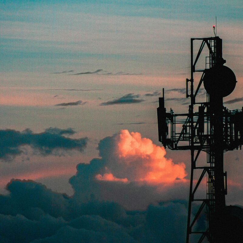 A metal tower with antennae high above the clouds against an evening sky