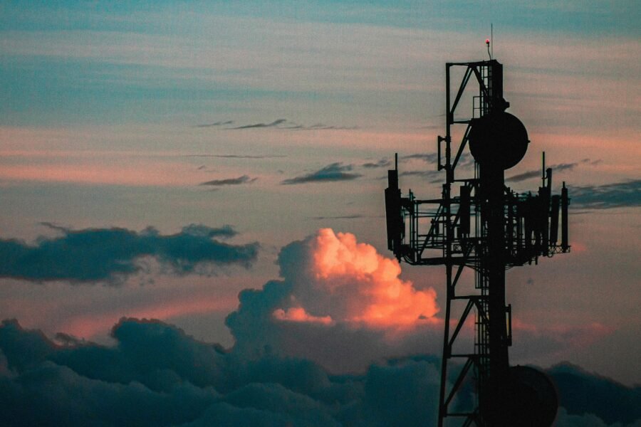 A metal tower with antennae high above the clouds against an evening sky
